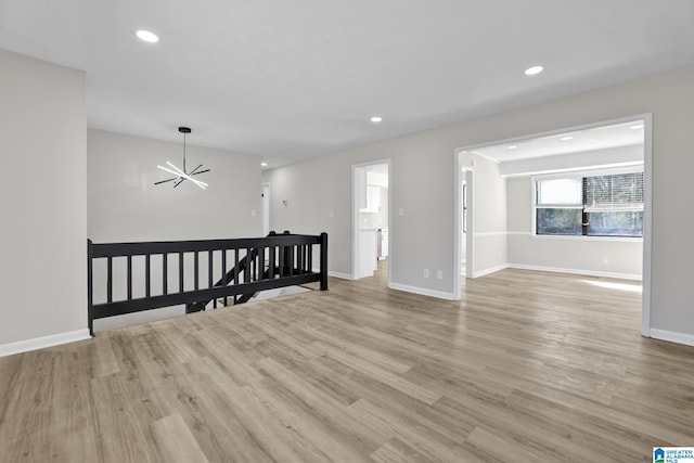 unfurnished room with light wood-style floors, baseboards, a notable chandelier, and recessed lighting