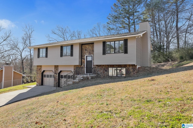 bi-level home featuring a garage, stone siding, concrete driveway, a front lawn, and a chimney