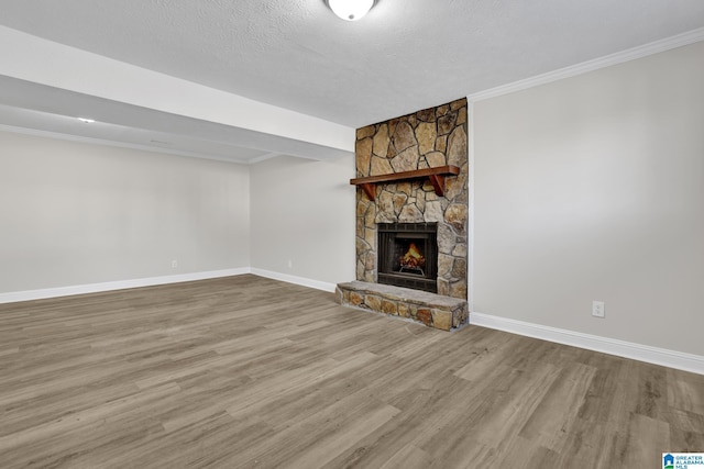 unfurnished living room with baseboards, ornamental molding, wood finished floors, a textured ceiling, and a fireplace