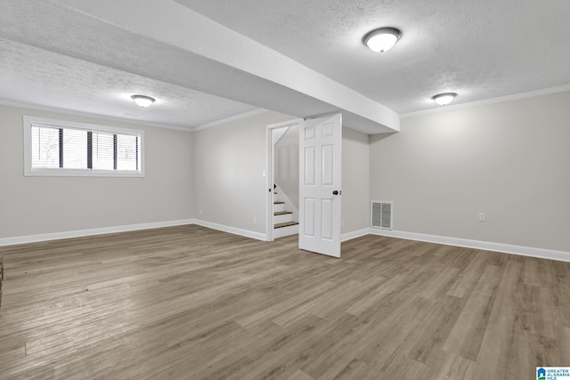 basement with visible vents, ornamental molding, wood finished floors, baseboards, and stairs