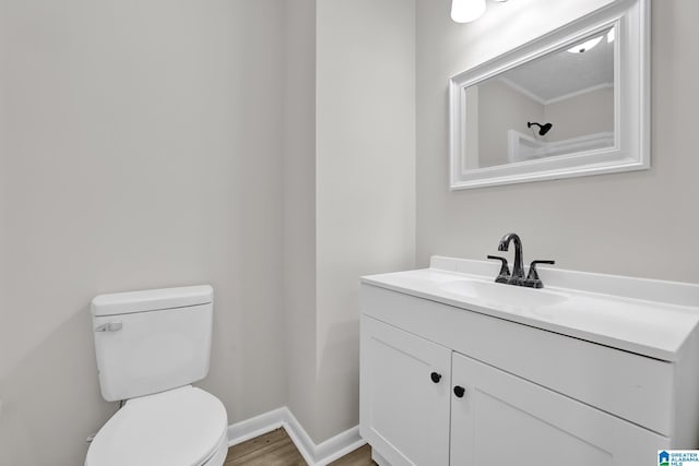 bathroom featuring toilet, baseboards, wood finished floors, and vanity