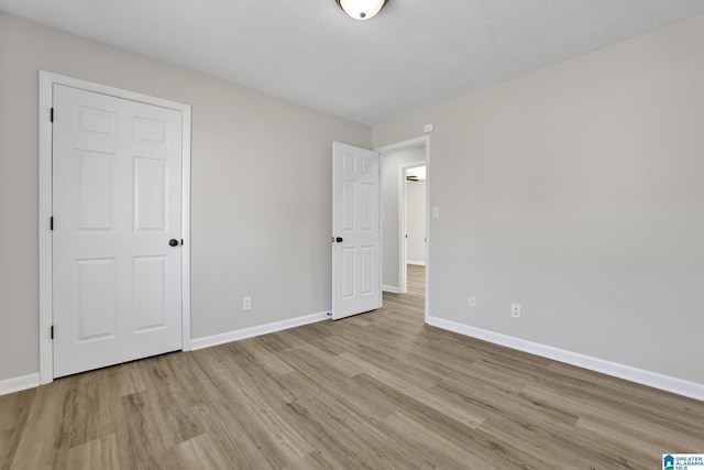 unfurnished bedroom with wood finished floors and baseboards