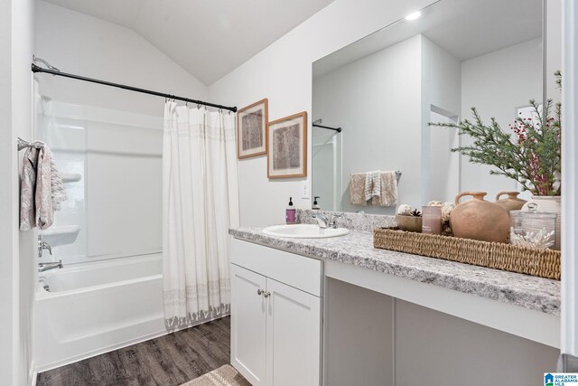 full bath featuring shower / bathtub combination with curtain, vaulted ceiling, wood finished floors, and vanity