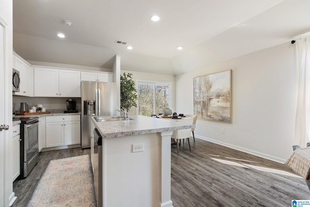 kitchen with visible vents, an island with sink, vaulted ceiling, stainless steel appliances, and light countertops