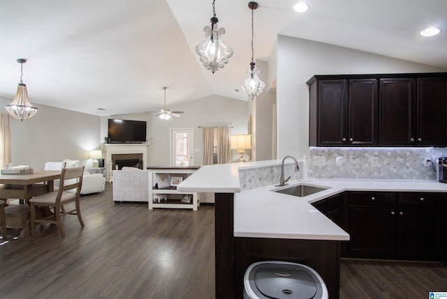 kitchen with sink, vaulted ceiling, hanging light fixtures, dark hardwood / wood-style floors, and decorative backsplash