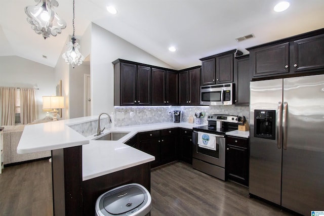 kitchen with sink, appliances with stainless steel finishes, backsplash, hanging light fixtures, and kitchen peninsula