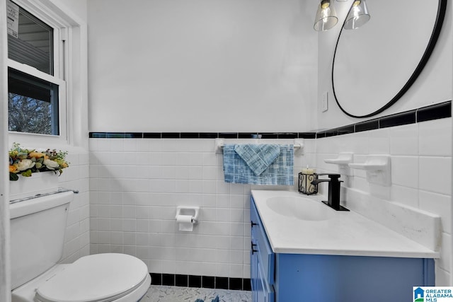 bathroom featuring vanity, toilet, and tile walls