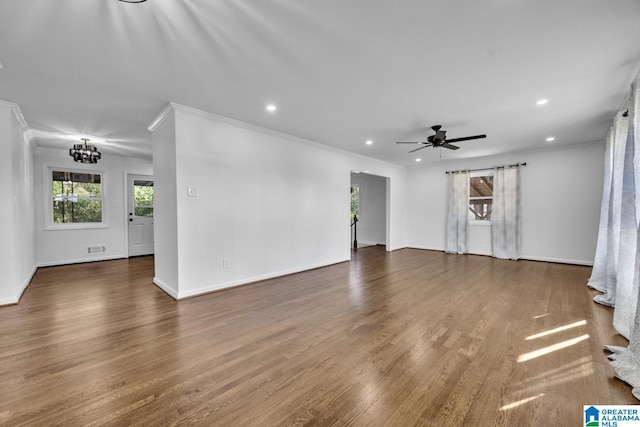 unfurnished living room featuring dark hardwood / wood-style flooring, ceiling fan with notable chandelier, and crown molding