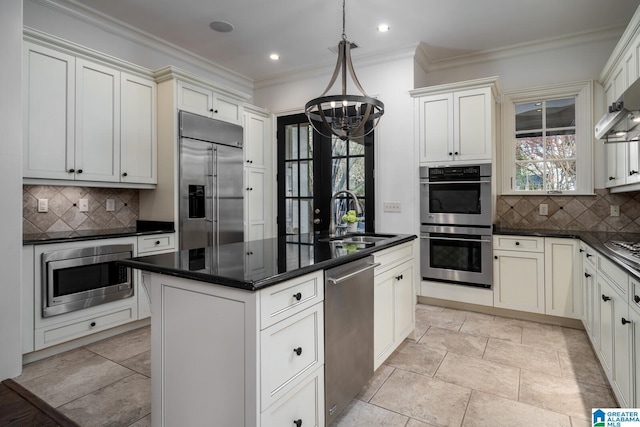 kitchen featuring decorative light fixtures, sink, backsplash, a center island, and built in appliances