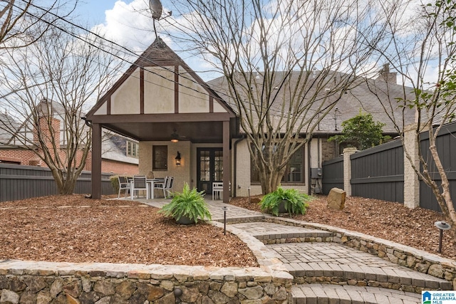 tudor-style house featuring french doors, ceiling fan, and a patio area