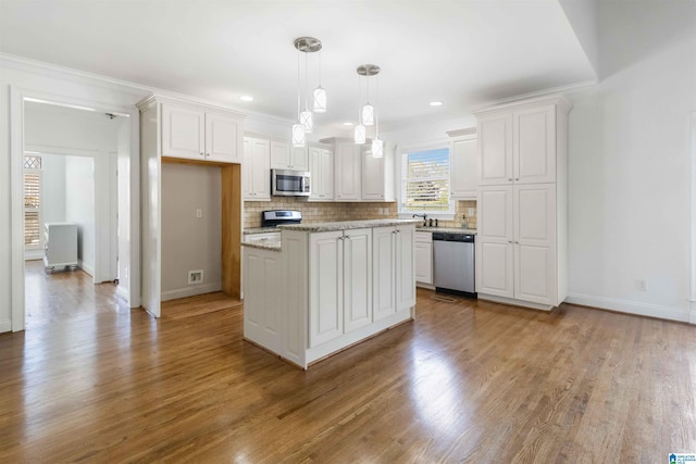 kitchen with pendant lighting, white cabinetry, a center island, light stone counters, and stainless steel appliances