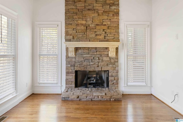 unfurnished living room featuring a stone fireplace and light hardwood / wood-style floors