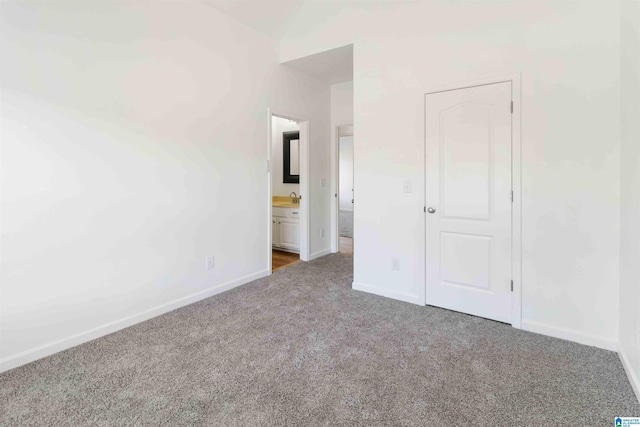 unfurnished bedroom featuring carpet, sink, lofted ceiling, and ensuite bath