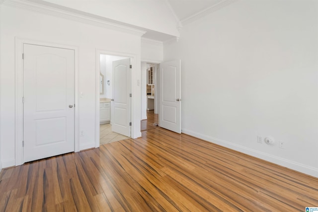 unfurnished bedroom with crown molding, vaulted ceiling, light hardwood / wood-style floors, and ensuite bathroom