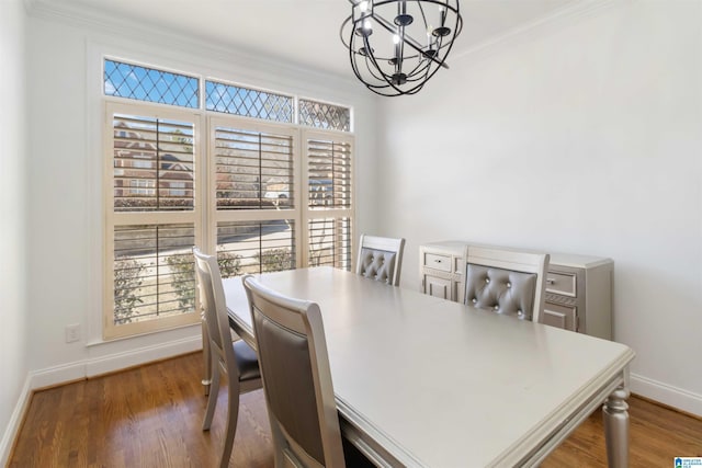 dining area featuring dark wood-type flooring, ornamental molding, and an inviting chandelier