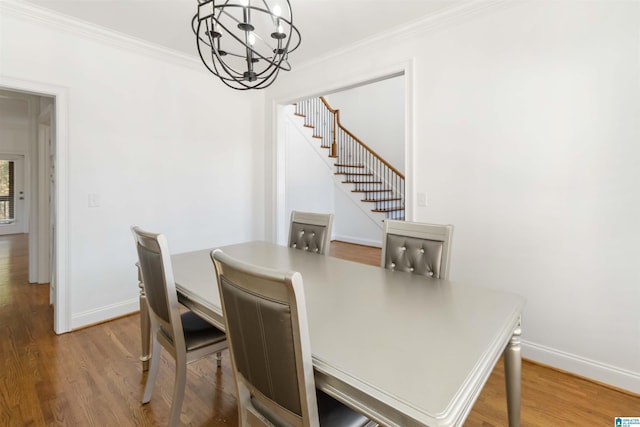 dining area with an inviting chandelier, hardwood / wood-style floors, and ornamental molding