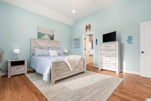 bedroom featuring lofted ceiling, ensuite bath, light hardwood / wood-style floors, and ceiling fan