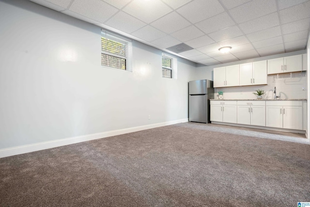 kitchen with sink, a paneled ceiling, stainless steel fridge, carpet floors, and white cabinets