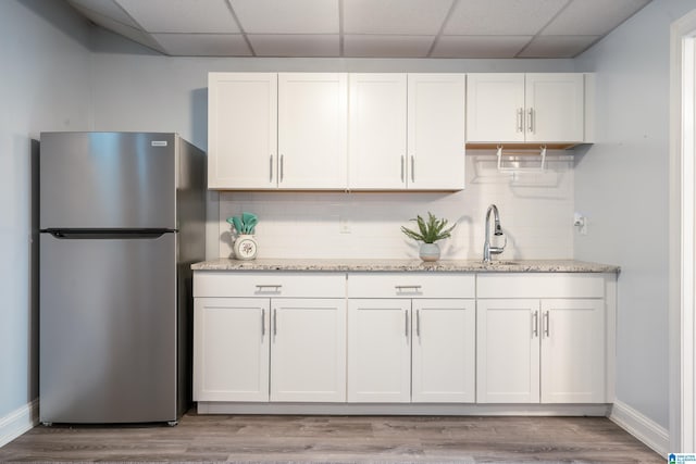 kitchen featuring tasteful backsplash, white cabinetry, a paneled ceiling, and stainless steel refrigerator