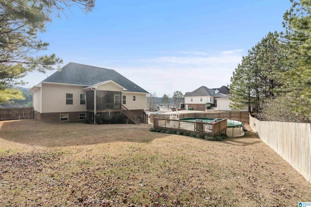 back of property with a fenced in pool, a sunroom, and a lawn