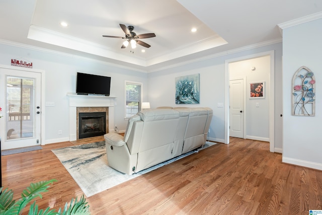 living room with crown molding, ceiling fan, a tray ceiling, and light hardwood / wood-style floors