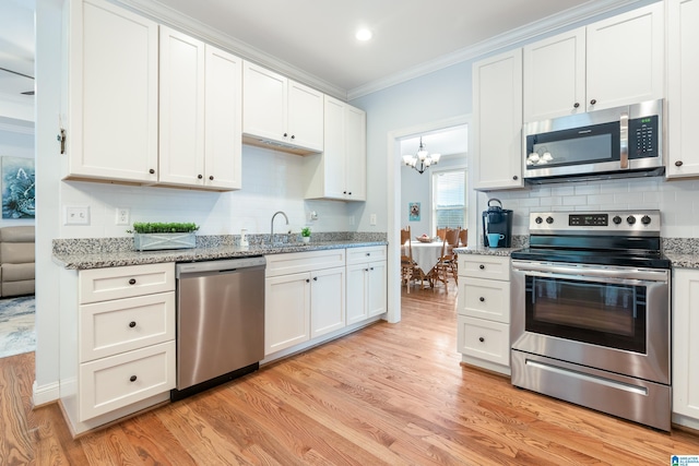 kitchen with ornamental molding, stainless steel appliances, and white cabinets