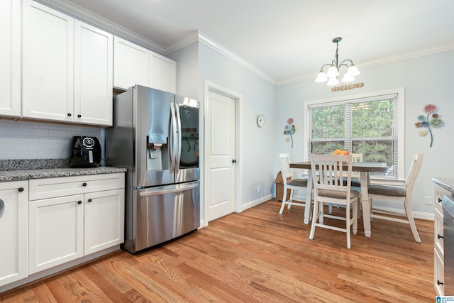 kitchen featuring tasteful backsplash, hanging light fixtures, light wood-type flooring, stainless steel fridge, and white cabinets