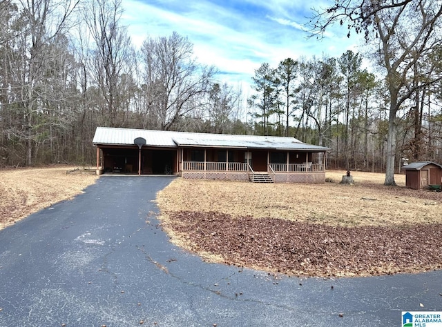 view of front of house featuring a porch, a carport, and a storage unit