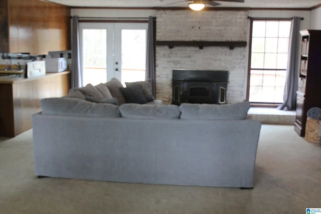 carpeted living room featuring french doors, ceiling fan, ornamental molding, and a fireplace