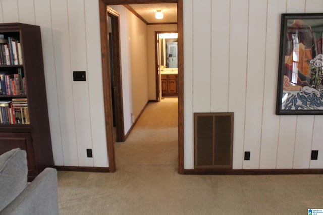 corridor with crown molding and light carpet