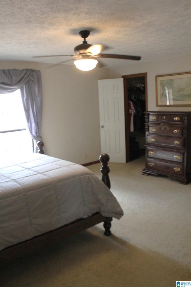 carpeted bedroom featuring ceiling fan and a textured ceiling