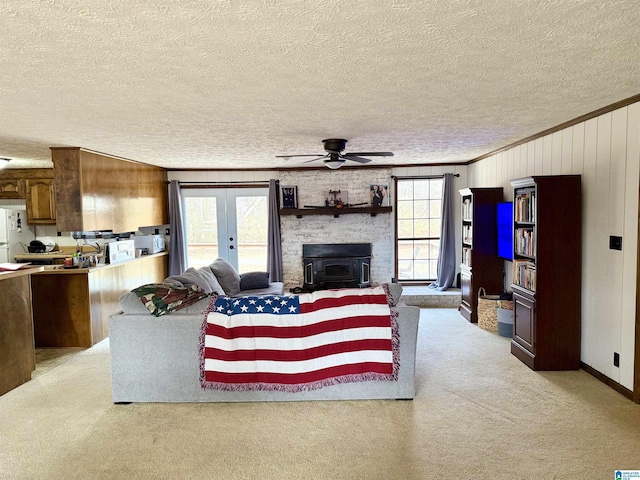 carpeted living room with ornamental molding, plenty of natural light, a wood stove, and french doors