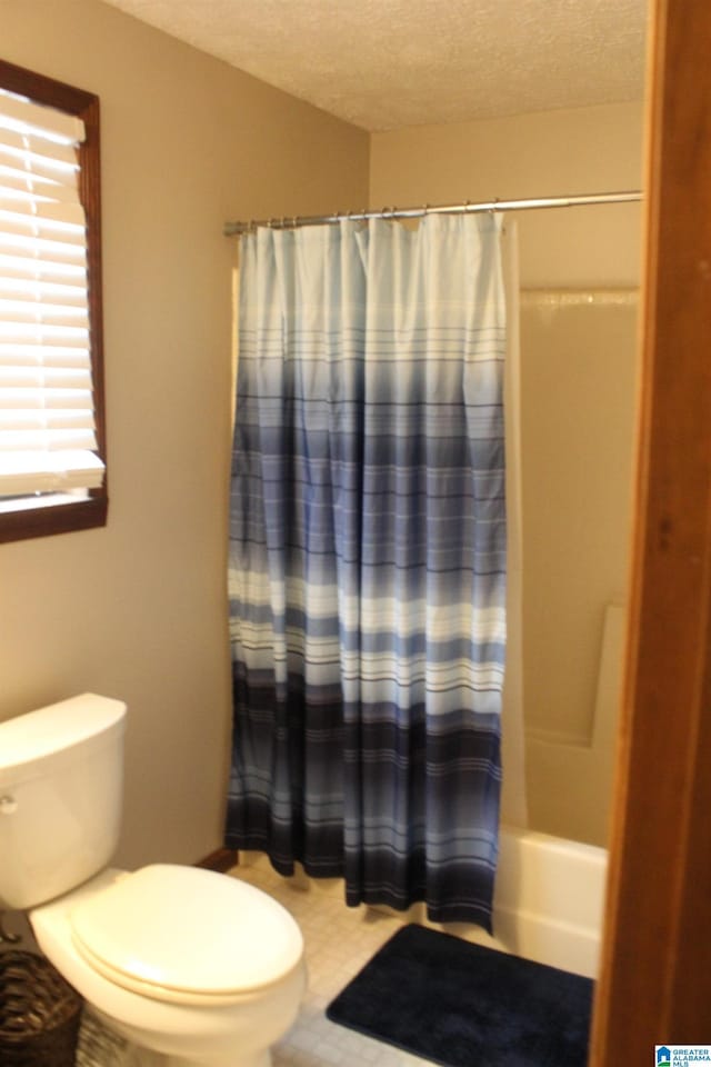 bathroom featuring a textured ceiling, shower / bath combination with curtain, and toilet