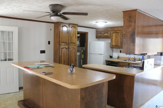 kitchen with sink, crown molding, a textured ceiling, a kitchen island, and white fridge