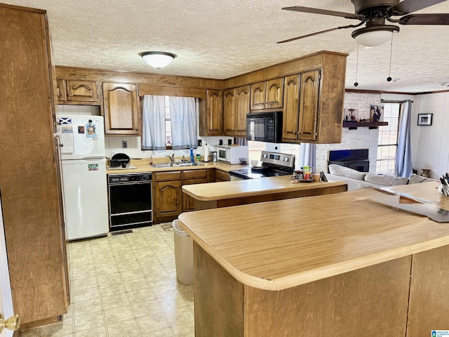 kitchen with a fireplace, a wealth of natural light, black appliances, and kitchen peninsula