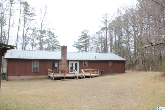 rear view of house with a yard, a deck, and french doors