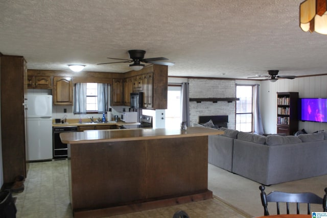 kitchen with sink, a fireplace, black appliances, and ceiling fan