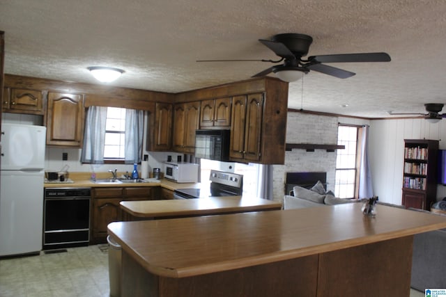 kitchen with sink, a fireplace, black appliances, and kitchen peninsula