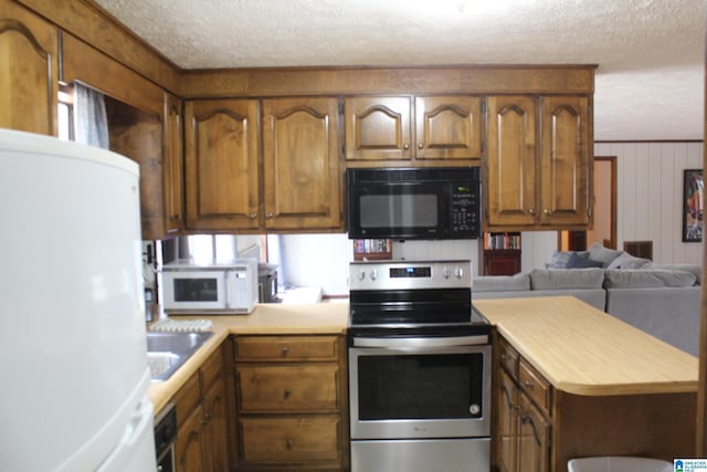 kitchen with sink, a textured ceiling, white appliances, and kitchen peninsula