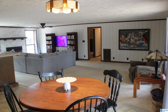 carpeted dining space with ceiling fan, a large fireplace, and a textured ceiling