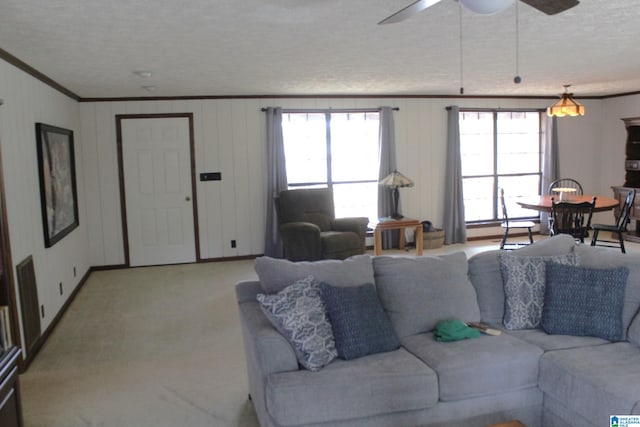 living room with crown molding, ceiling fan, light carpet, and a textured ceiling