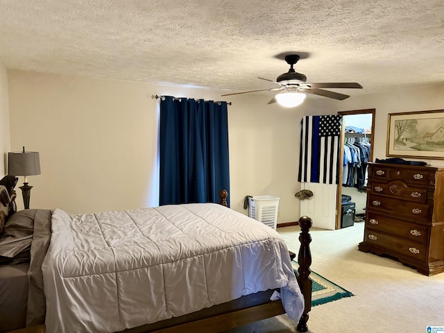 carpeted bedroom with a spacious closet, a textured ceiling, a closet, and ceiling fan