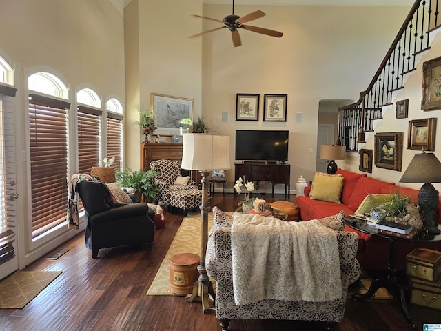 living room with dark wood-type flooring, a towering ceiling, and ceiling fan