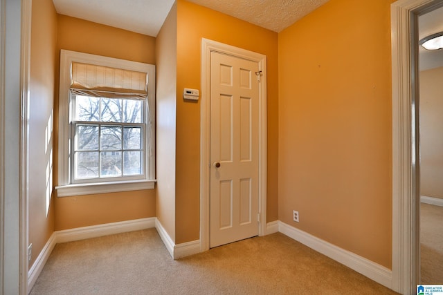 corridor featuring light carpet and a textured ceiling