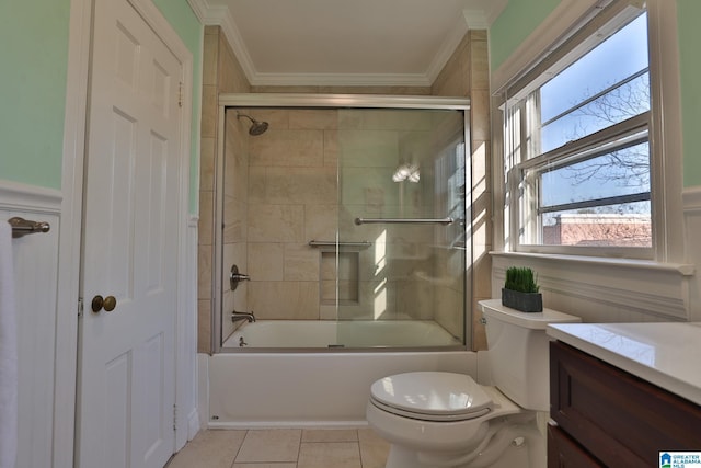 full bathroom with tile patterned floors, toilet, combined bath / shower with glass door, crown molding, and vanity