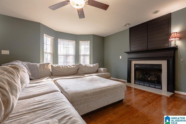 living room featuring wood-type flooring, ceiling fan, and a fireplace