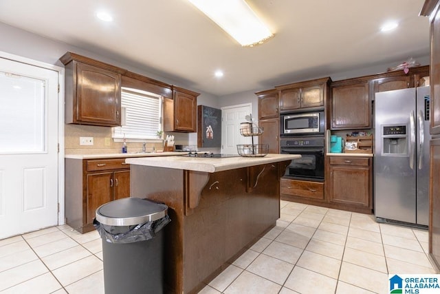 kitchen featuring light tile patterned floors, sink, backsplash, stainless steel appliances, and a kitchen island