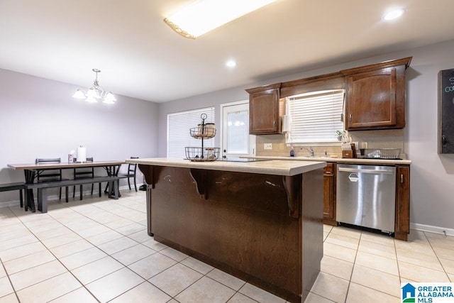 kitchen with hanging light fixtures, light tile patterned floors, stainless steel dishwasher, and a center island