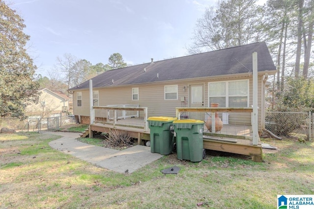 back of property with a wooden deck and a lawn