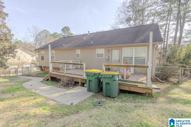 rear view of house featuring a wooden deck and a lawn